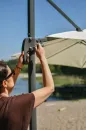 woman_working_on_the_mechanism_of_a_beige_umbrella_with_a_side_pole_ca64.webp